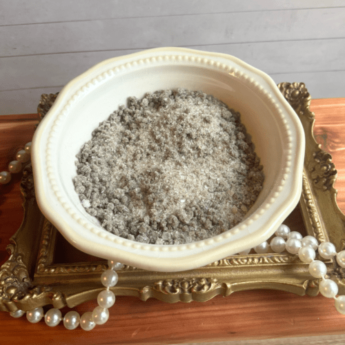 Small bowl of Mineral Springs bath salt sitting on a gold frame with pearls