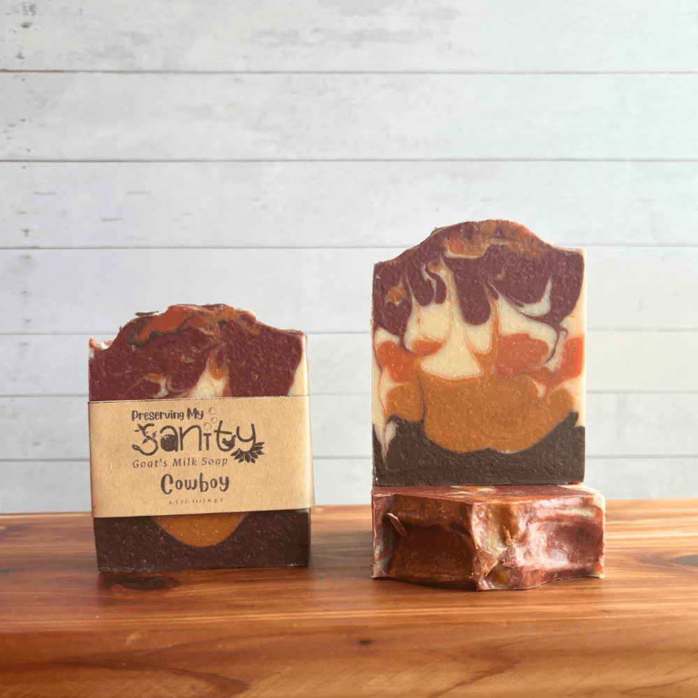 Front view of three bars of Cowboy goat milk soap showing the label, top, and full front of bar