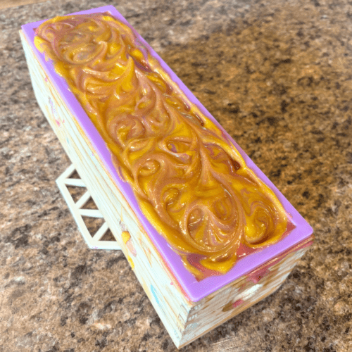 Process photo showcasing a freshly poured loaf of Nag Champa goat milk soap with a pretty swirled top