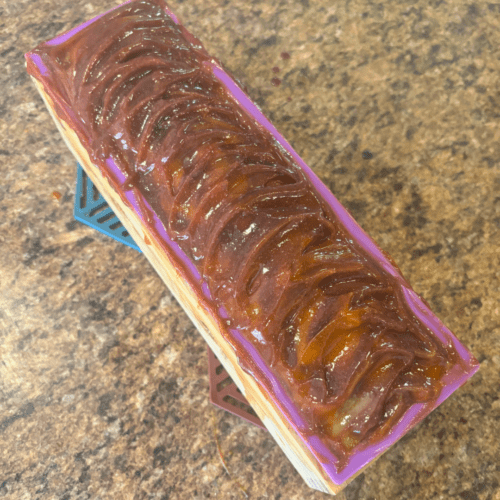 Process photo showcasing a freshly poured loaf of Orange Patchouli goat milk soap with a pretty textured top