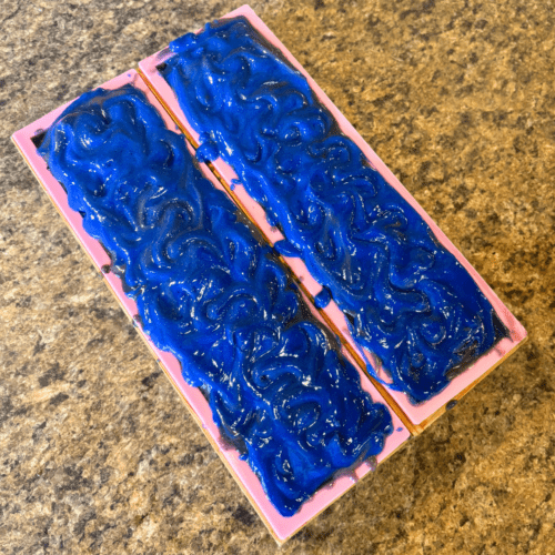 Process photo showcasing two loaves of freshly poured Starry Night goat milk soap with bright blue textured tops