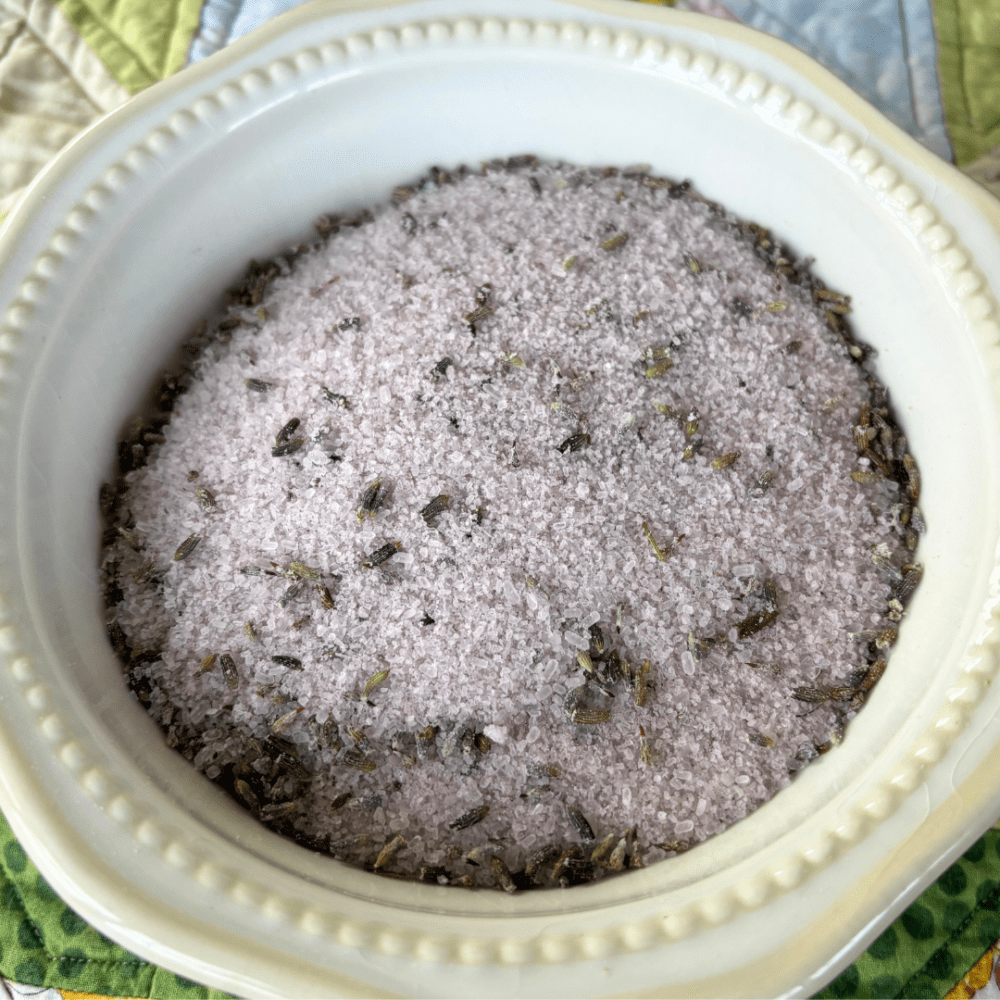 Pretty white bowl filled with lavender and green tea bath tea, sitting on a spring tablecloth