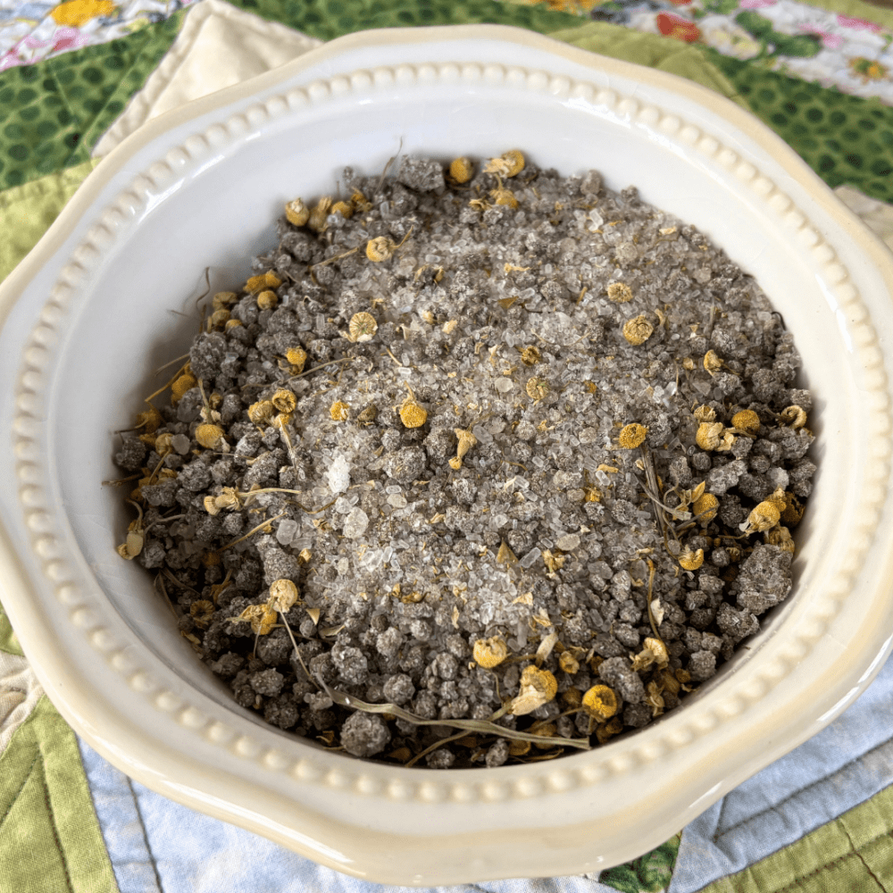 Pretty white bowl filled with mineral springs and chamomile bath tea, sitting on a spring tablecloth