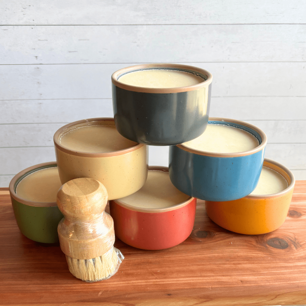 Alternate view of display photo showcasing six colorful ramekins of cold process dish soap made with coconut oil and essential oils. Pictured with an eco-friendly bamboo dish brush.