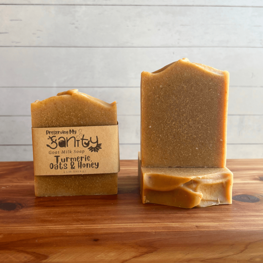 Alternate view display photo showcasing three unscented bars of Turmeric, Oats & Honey soap sitting on a cedar board with a white shiplap background