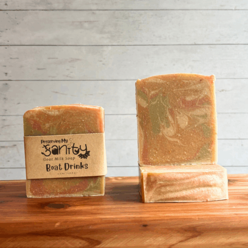 Display photo showcasing three bars of swirled Boat Drinks soap. One bar has a label, the other two are without labels and situated to show the top and front of the bar. Colors used are light pink, orange, green, and white for a really pretty pastel soap bar.