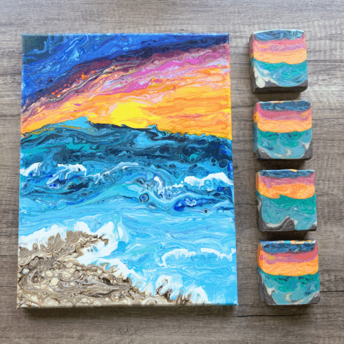 Flatlay photo showing the painting that inspired this pretty 16-color soap that was made for the April Soap Challenge Club. Painting is accompanied by four bars of Candy Sunset goat milk soap. Scented with a bright and fresh beachy scent, this colorful goat milk soap is a limited edition creation.