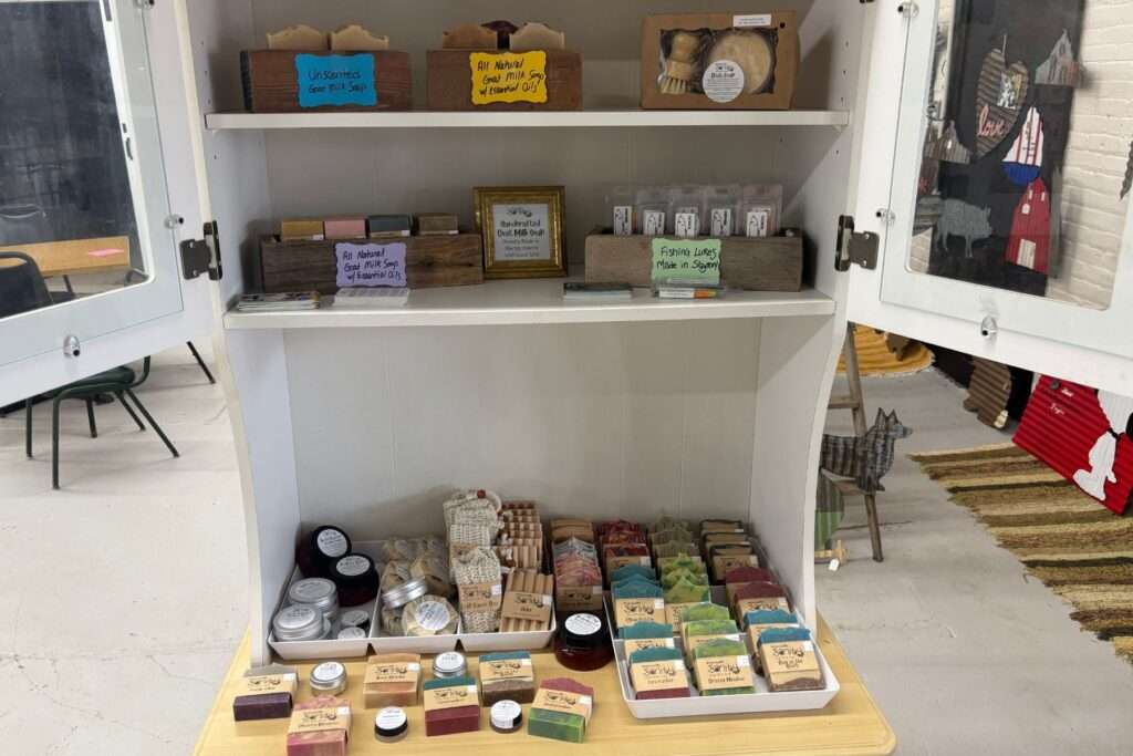 Photo of Preserving My Sanity goat milk soap display at The Corner Marketplace in Tyler, MN showcasing a variety of goat milk soap, salves, balms, fishing lures, dish soap, and more.