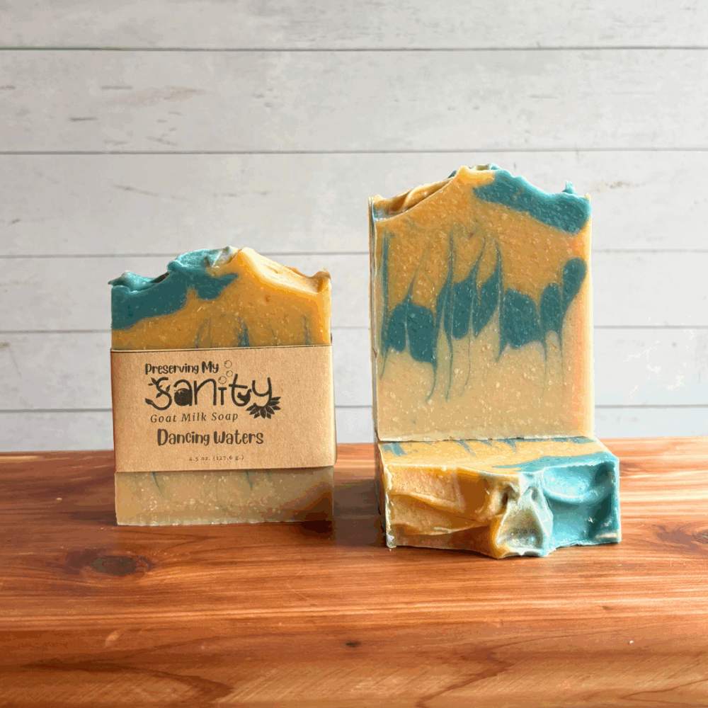 Three bars of Dancing Waters goat milk soap. Soap is a unique swirl of blue, gold, and uncolored soap. Two bars are displayed to show the design and top of the bars, while the third shows the label.