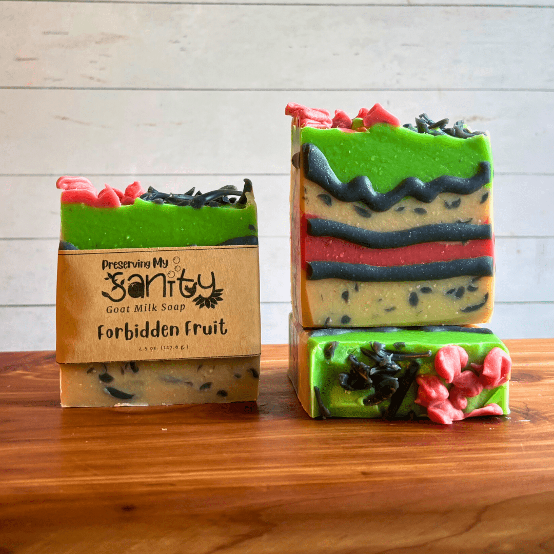 Three bars of Forbidden Fruit goat milk soap. This soap was created as part of my paranormal collection, but also for the comic cakes Soap Challenge Club contest. Soap has layers of white, red, and green and is outlined with black piping and has charcoal sprinkle embeds. Two bars are displayed to show the design and top of the bars, while the third shows the label.