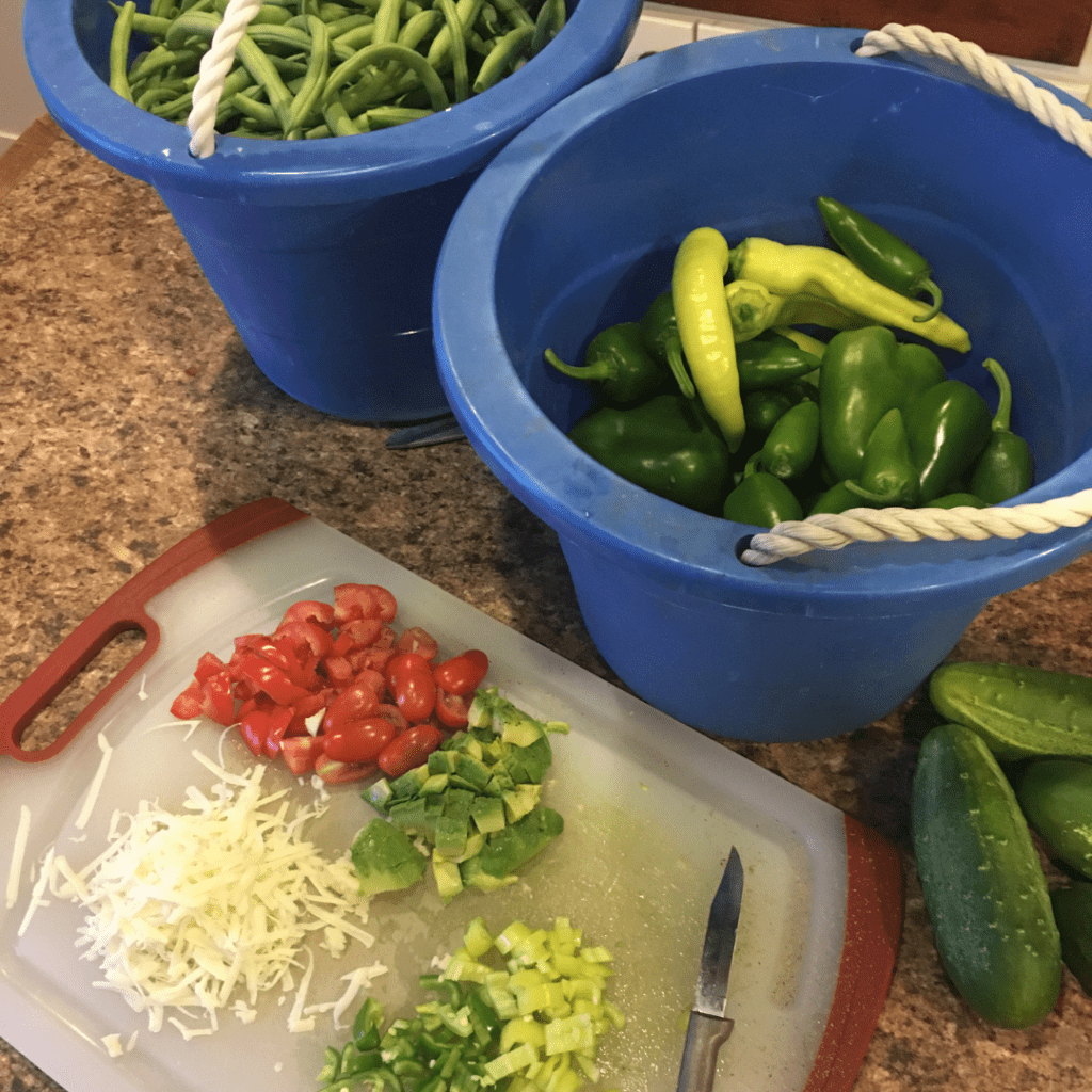 Photo of fresh produce in buckets and some chopped vegetables on a cutting board.