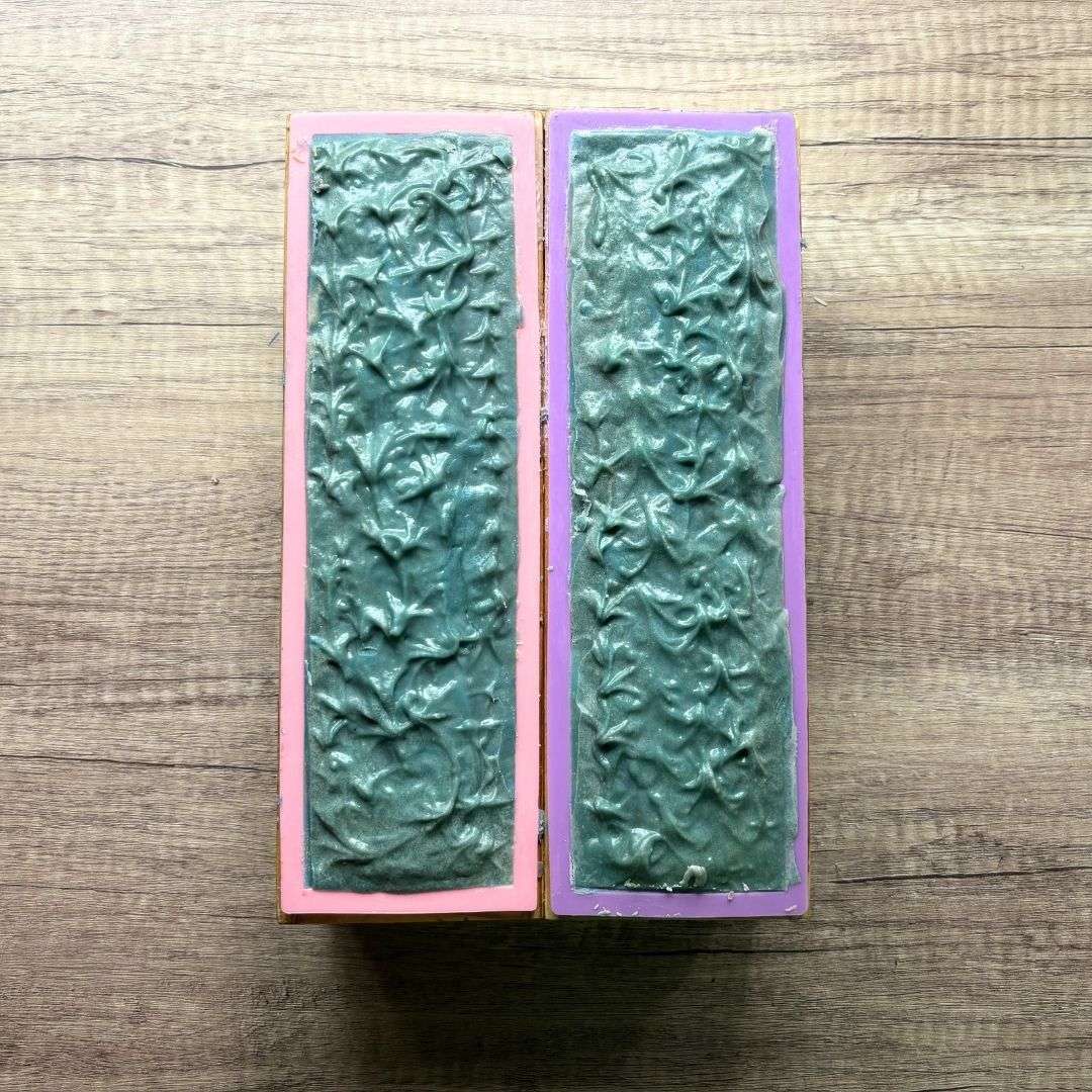Two Day at the Beach soap loaves rest in pink and purple silicone molds during the soapmaking process. The tops feature textured peaks and swirls in rich ocean blue, creating a wave-like pattern that reflects the soap's coastal inspiration. The handcrafted loaves are shown before being cut into individual bars.