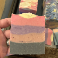 Photo of maker holding a freshly cut bar of Mixed Berry goat's milk soap